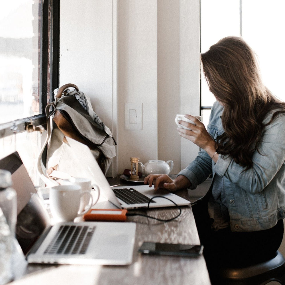 woman working on laptop drinking coffee for performance